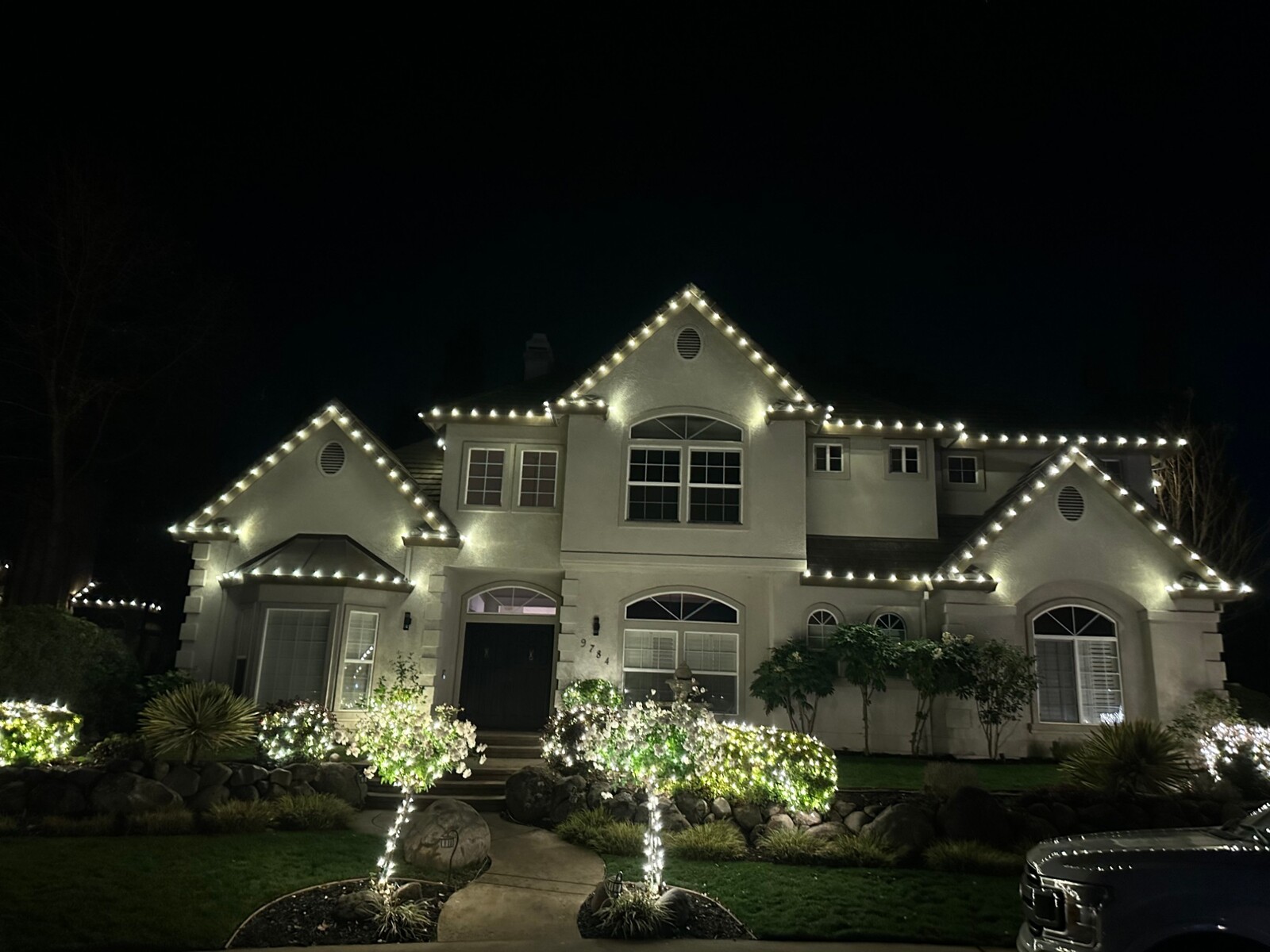 Christmas light installers in Auburn, CA: two story stucco pure white roofline lit shrubs tree wraps